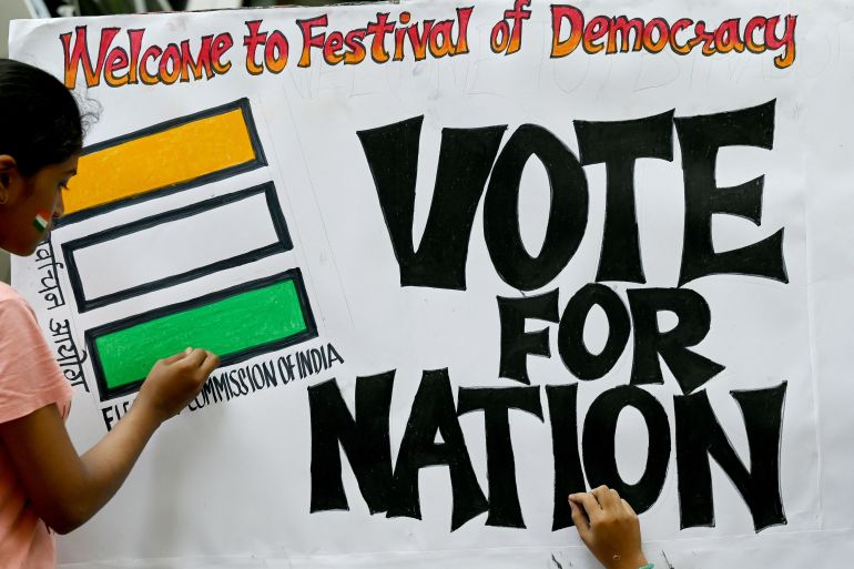 Art school students give finishing touches to an election themed painting placed along a street outside their class to encourage people to vote in India's upcoming general elections, in Mumbai on April 17, 2024